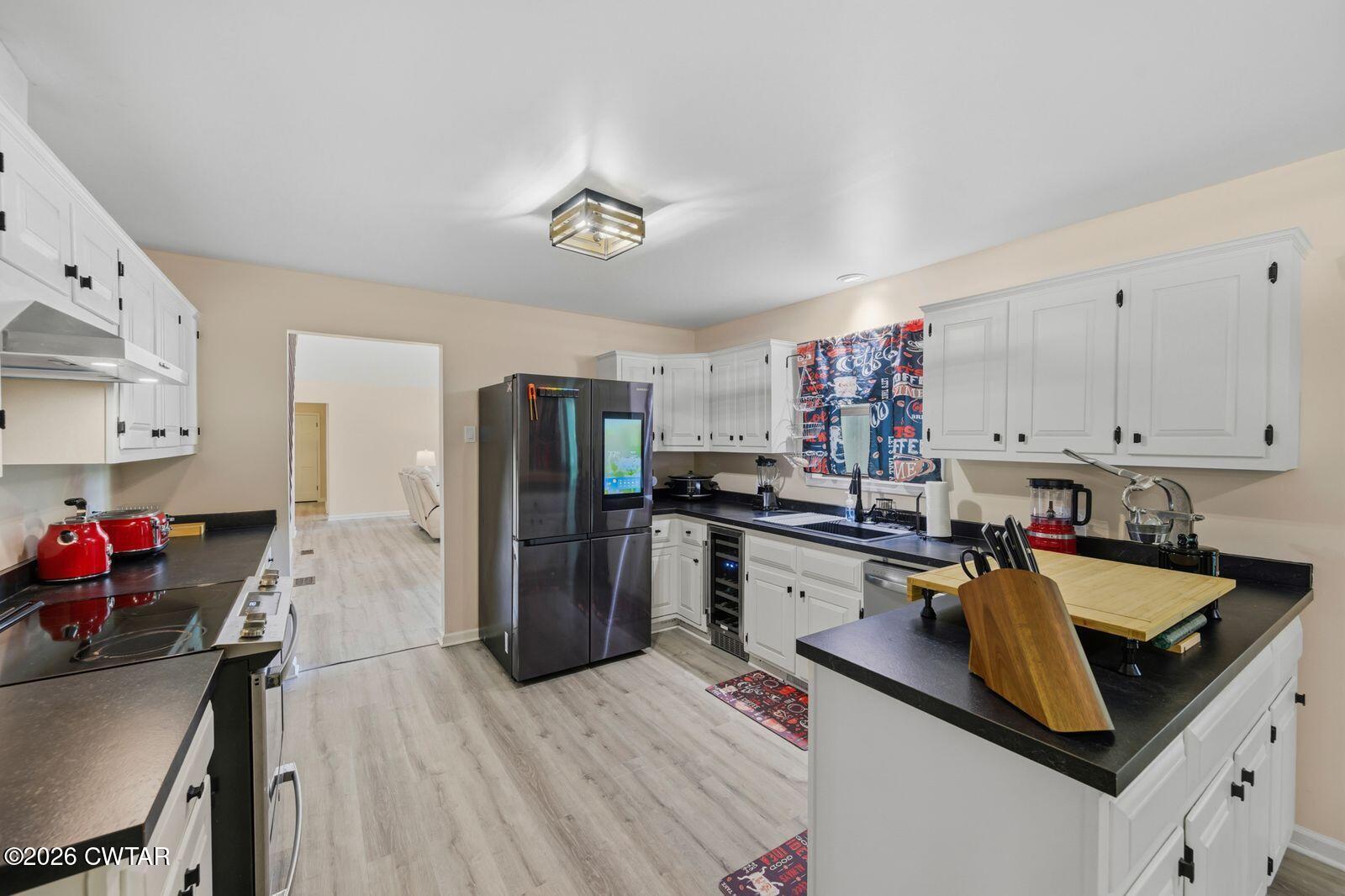 4110 Corinth Road Lexington, TN 38351 - Photo 13 of 59 a kitchen with stainless steel appliances granite countertop a refrigerator a sink dishwasher a stove and white countertops with wooden floor