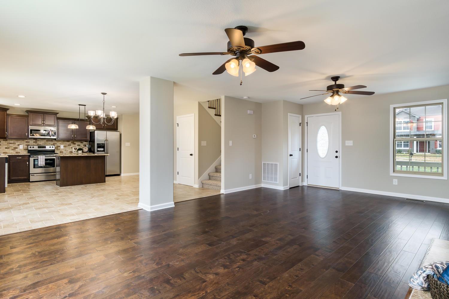 2645 Mockingbird Hill Road Palmyra, TN 37142 - Photo 8 of 27 an empty room with wooden floor ceiling fan and kitchen view