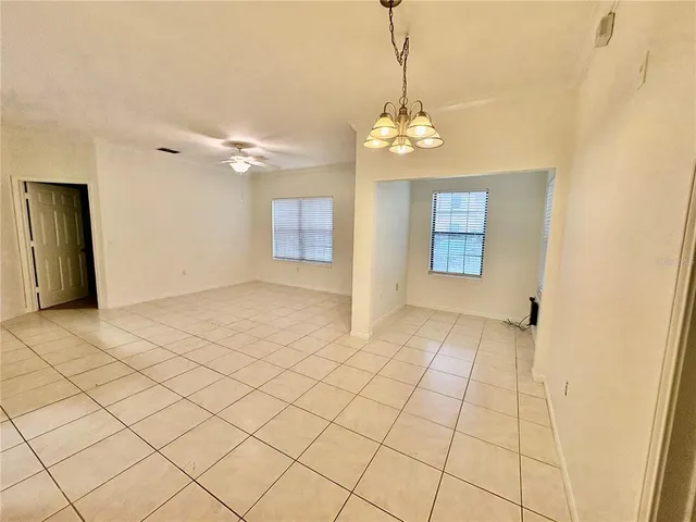 a view of a livingroom with a chandelier fan and windows