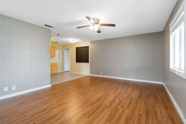 a view of an empty room with wooden floor and window
