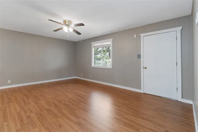 a view of an empty room with wooden floor and window