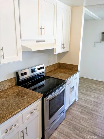 a kitchen with granite countertop a stove and a white cabinets