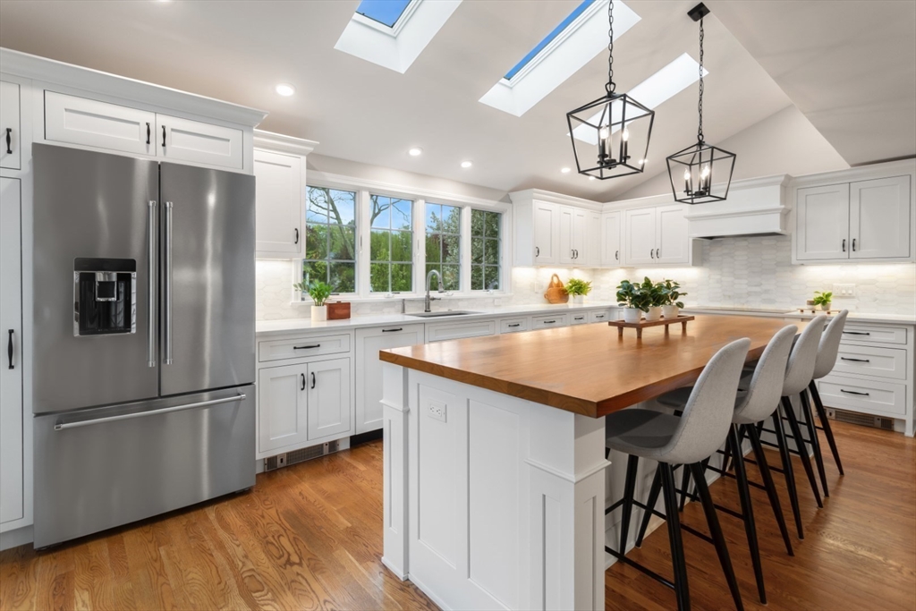 32 Sturges Road Reading, MA 01867 - Photo 7 of 39 a kitchen with granite countertop a refrigerator a sink dishwasher a stove a refrigerator and a dining table with wooden floor