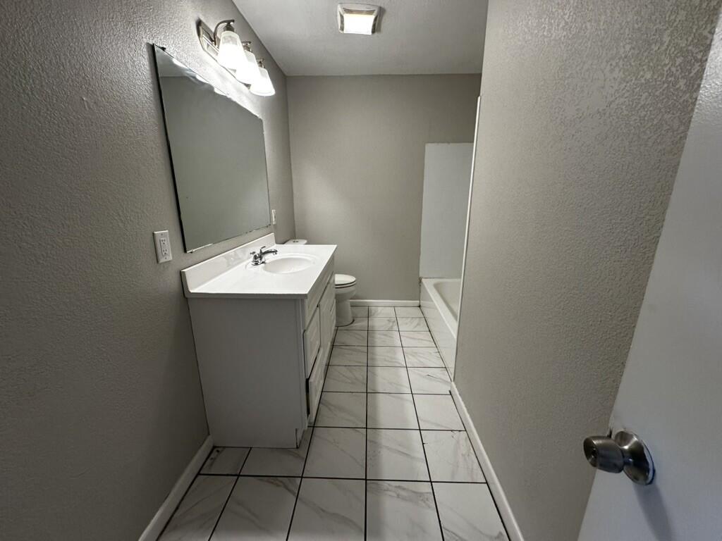 1602 39th Street Lubbock, TX 79412 - Photo 11 of 14 a bathroom with a sink a toilet and a mirror
