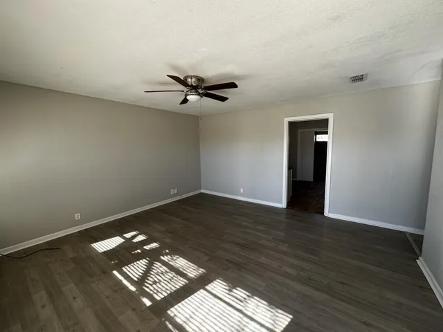 a view of a room with wooden floor and a ceiling fan