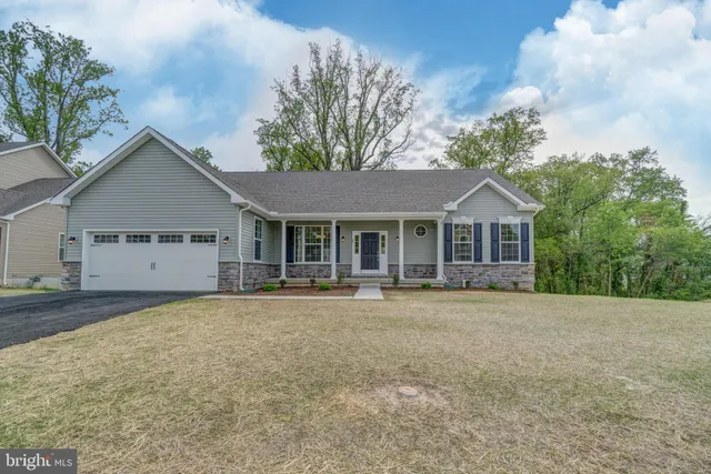 a front view of house with yard and trees in the background