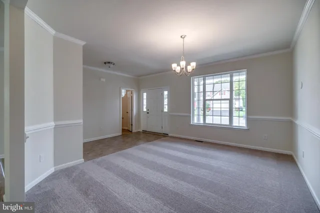 an empty room with chandelier and windows