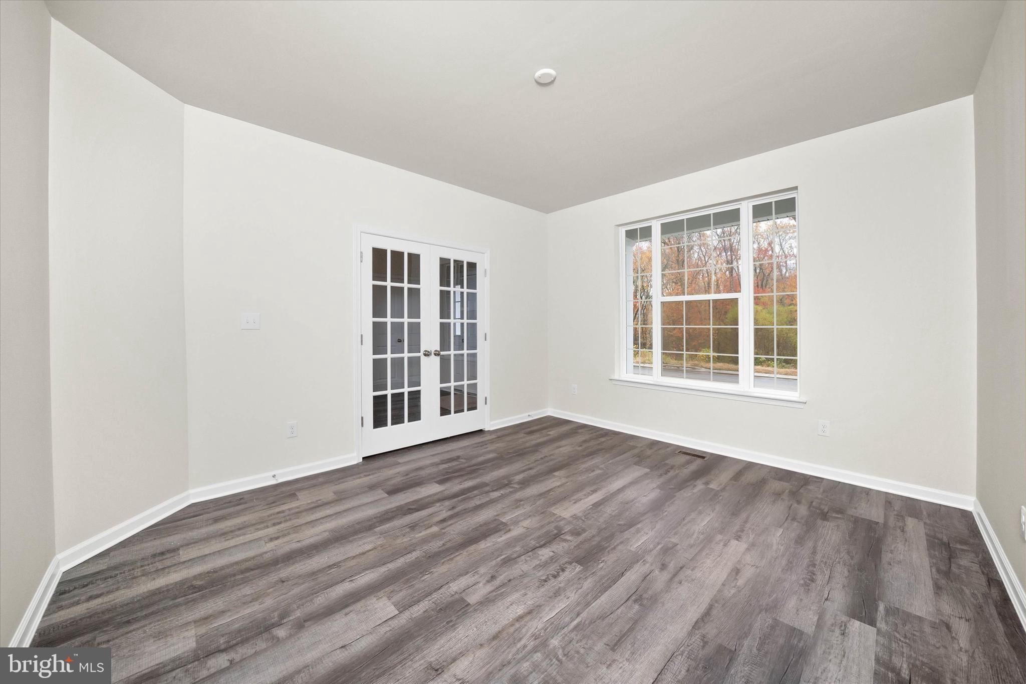 211 Laks Court, Unit JEFFERSON Smyrna, DE 19977 - Photo 6 of 22 a view of an empty room with wooden floor and windows