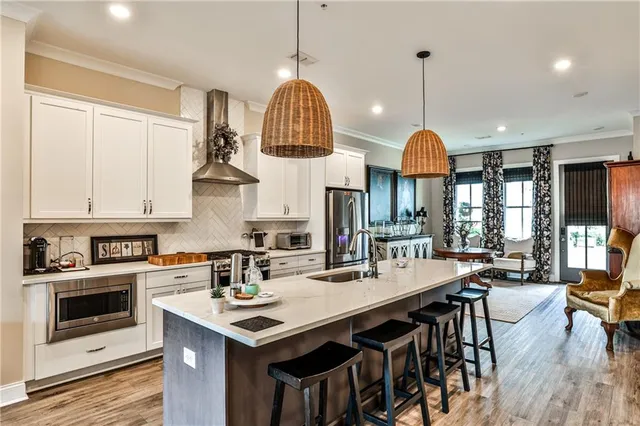 a kitchen with stainless steel appliances a stove a sink a oven a dining table and chairs
