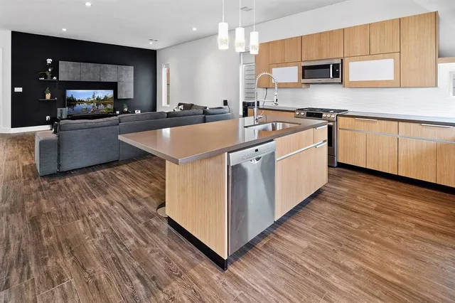 a kitchen with stainless steel appliances granite countertop a sink a stove and a wooden floors