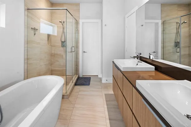 a bathroom with a tub a sink and a large mirror