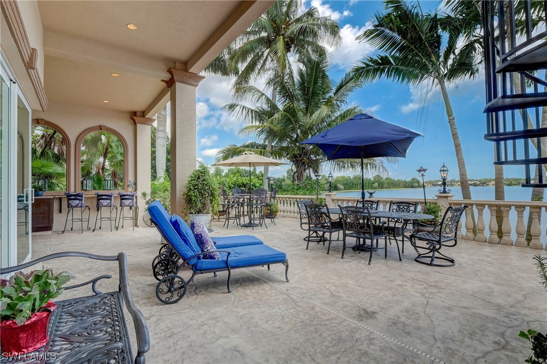 5960 Harborage Drive Fort Myers, FL 33908 - Photo 17 of 32 a view of a patio with a table and chairs under an umbrella with potted plants