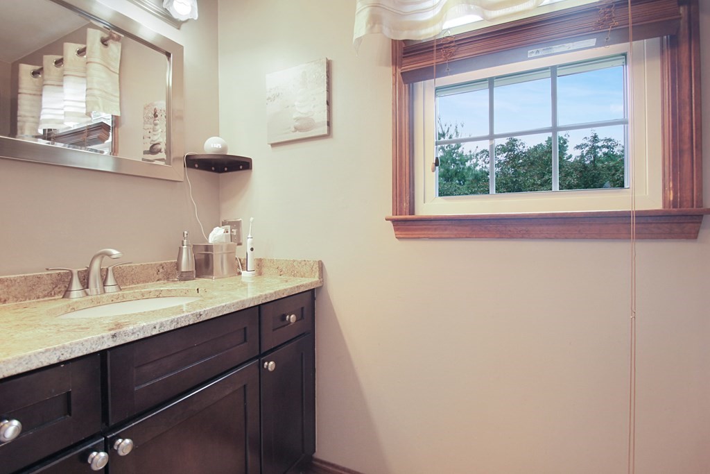 12 Indian Rock Road Haverhill, MA 01832 - Photo 18 of 31 a bathroom with a granite countertop sink a large mirror a vanity and a window