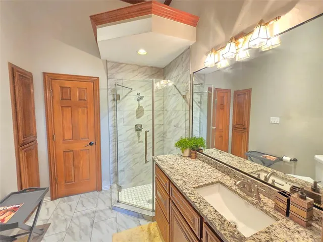 a spacious bathroom with a granite countertop sink a mirror and a shower