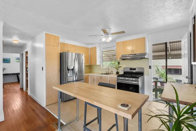 a kitchen with stainless steel appliances a stove a refrigerator a sink a dining table and chairs