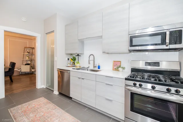 a kitchen with stainless steel appliances white cabinets and a stove top oven