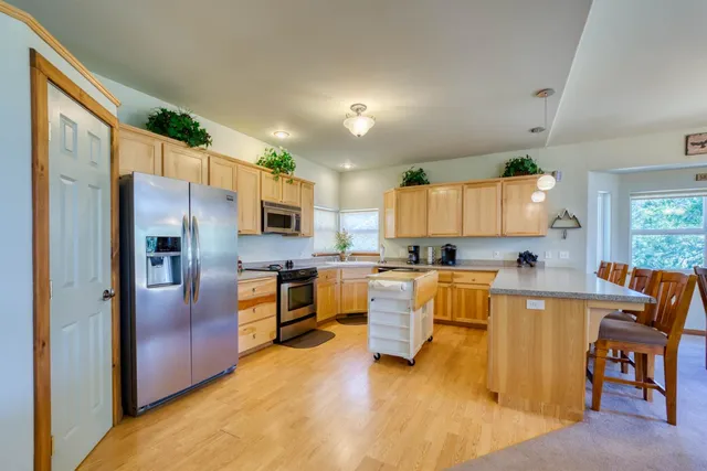a kitchen with stainless steel appliances granite countertop a refrigerator a stove top oven a sink dishwasher and white cabinets with wooden floor