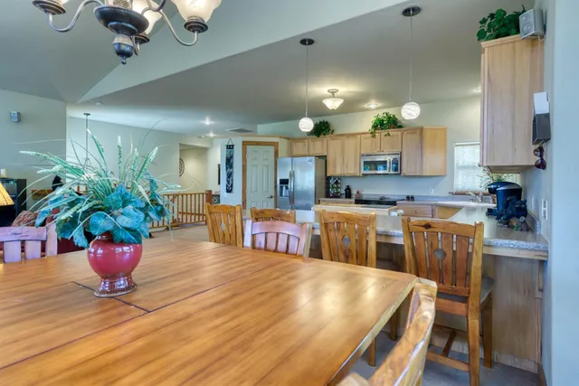 a kitchen with stainless steel appliances granite countertop a refrigerator a stove a sink dishwasher and a dining table with wooden floor