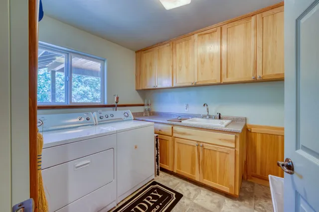 a utility room with stainless steel appliances granite countertop a sink and a cabinets