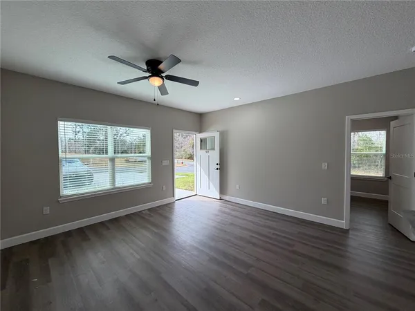 a view of an empty room with a window and wooden floor