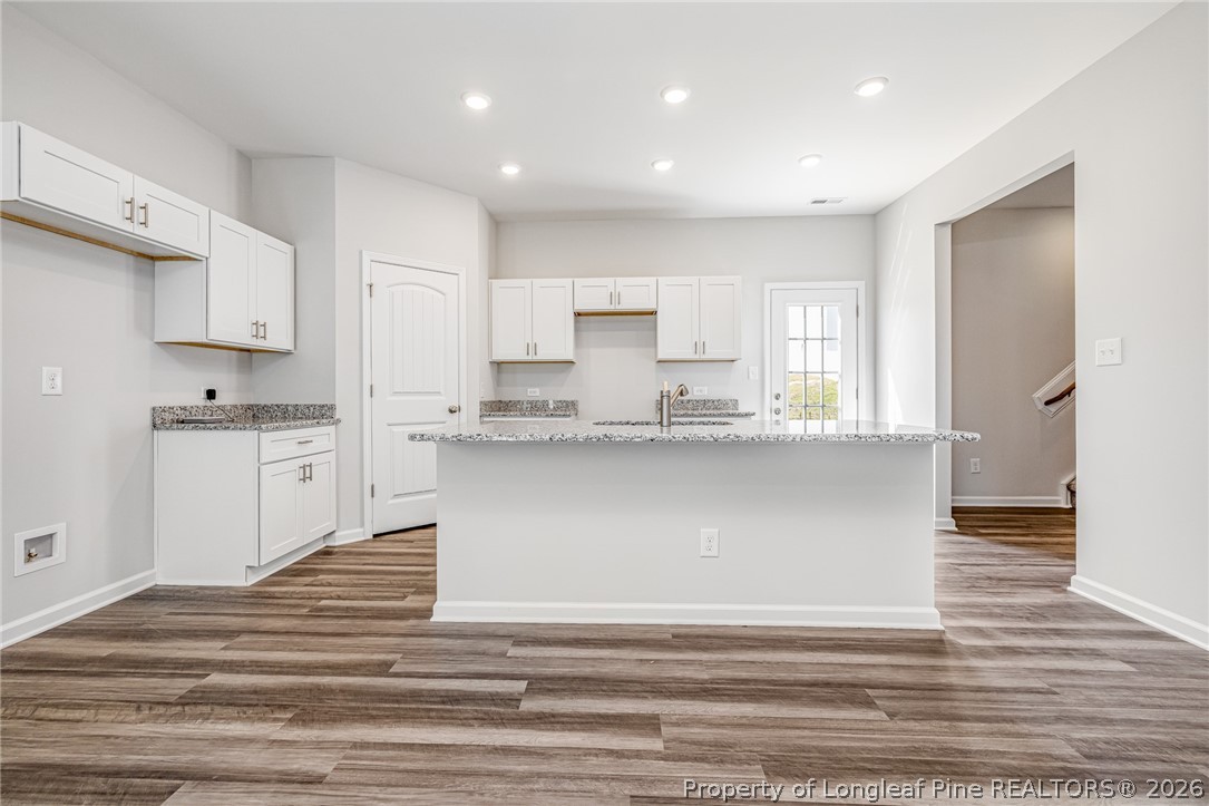 5413 Short Leaf Road Fayetteville, NC 28311 - Photo 6 of 33 a large white kitchen with kitchen island a sink wooden floor and a refrigerator