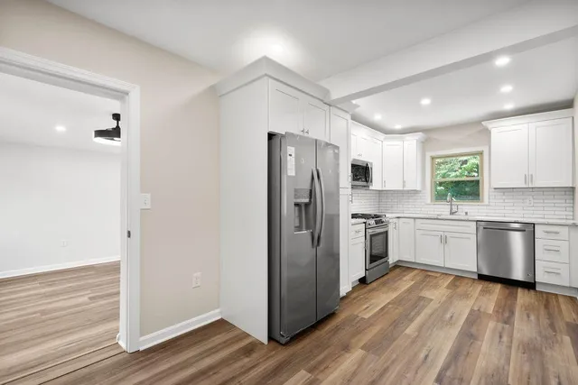 a kitchen with a refrigerator a stove top oven and wooden floor