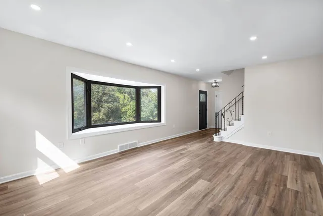 a view of an empty room with wooden floor and a window