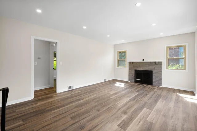 an empty room with wooden floor and fireplace