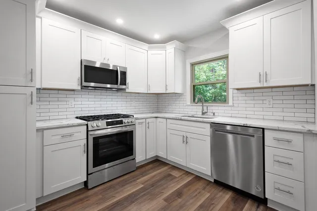 a kitchen with white cabinets stainless steel appliances and sink