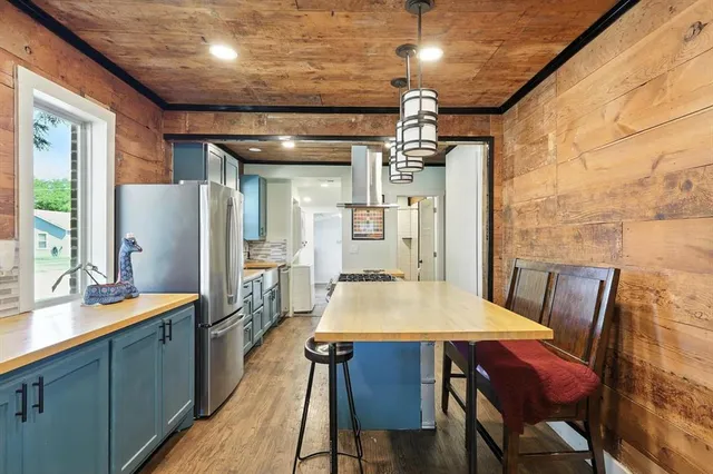 a kitchen with stainless steel appliances a table chairs and refrigerator
