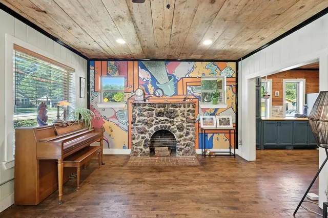 a living room with a fireplace furniture a ceiling fan and a large window