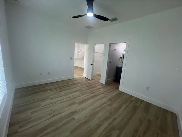 an empty room with wooden floor and a chandelier fan