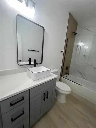 a bathroom with a sink a toilet a mirror and shower