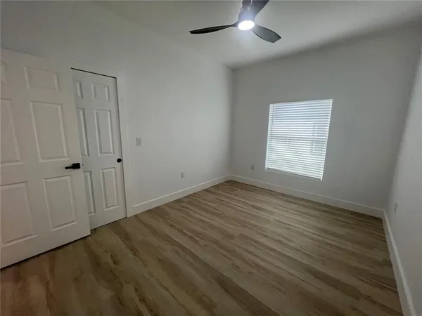 an empty room with wooden floor cabinet and windows