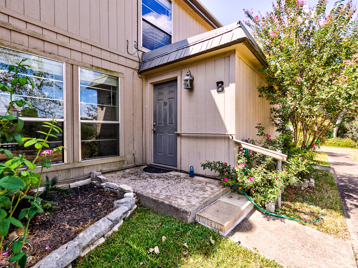 710 Castle Ridge Road, Unit B Austin, TX 78746 - Photo 2 of 27 A welcoming front entrance awaits, framed by flourishing greenery and a convenient concrete path.