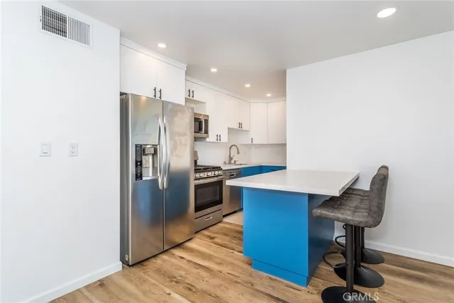 a kitchen with stainless steel appliances a refrigerator a stove a sink cabinets and wooden floor