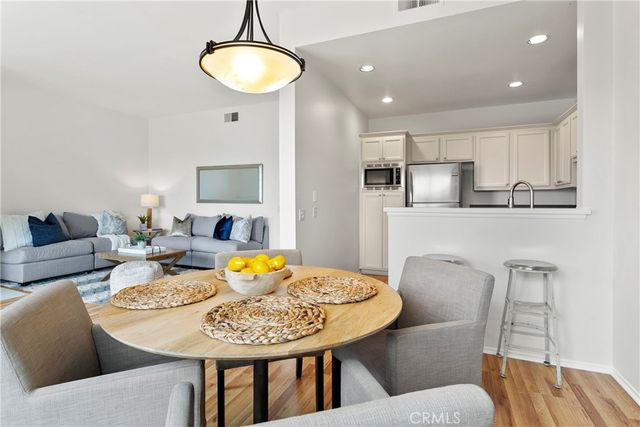 a kitchen with stainless steel appliances granite countertop a refrigerator a stove a sink and white cabinets with wooden floor