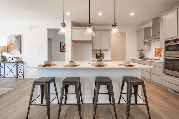 a kitchen with stainless steel appliances granite countertop a table chairs stove and wooden floor