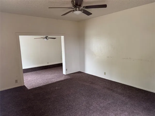 an empty room with a ceiling fan and carpet