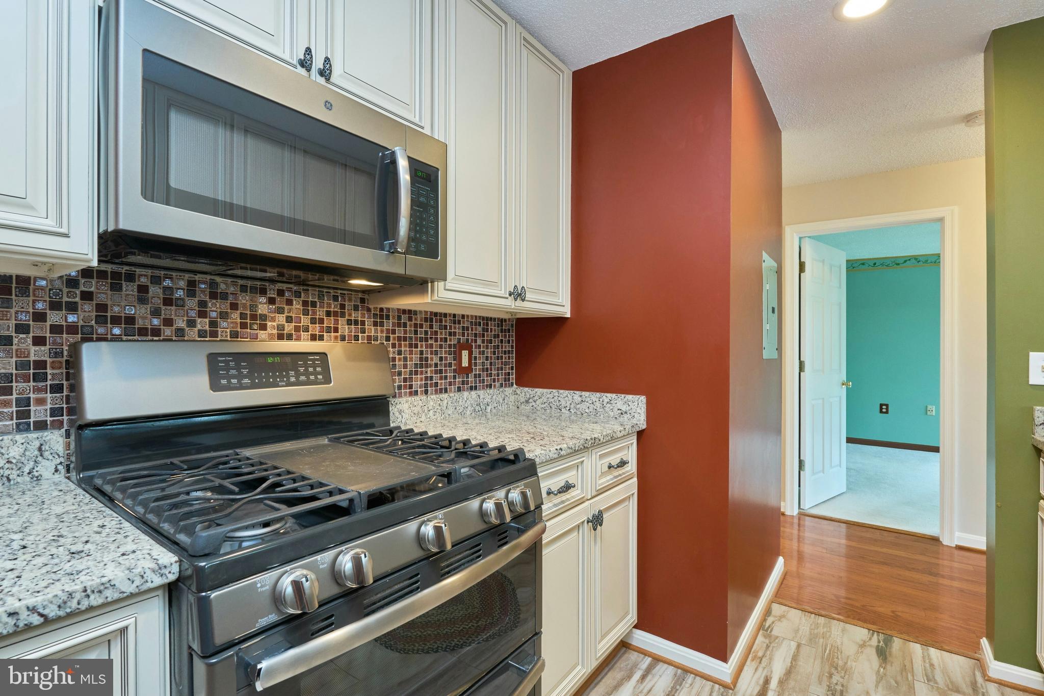 21014 Timber Ridge Terrace, Unit 302 Ashburn, VA 20147 - Photo 22 of 32 a kitchen with granite countertop a stove and a microwave