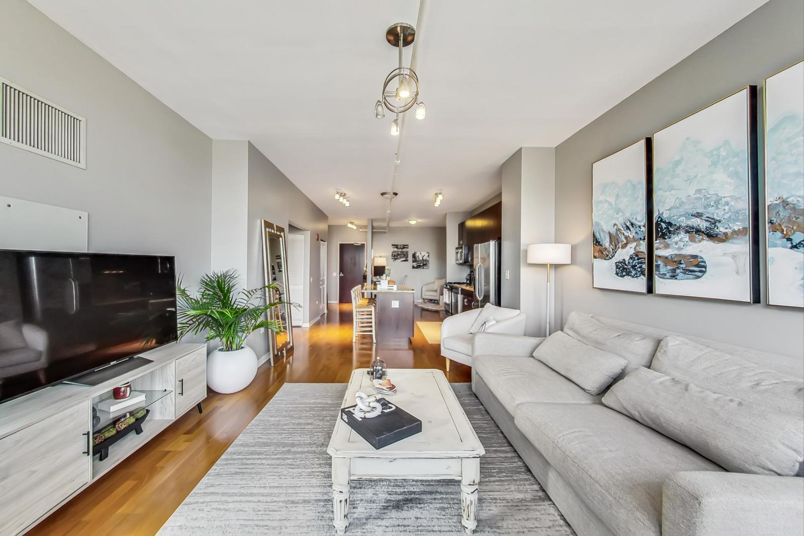 437 West Division Street, Unit 705 Chicago, IL 60610 - Photo 4 of 23 a living room with furniture a flat screen tv and a floor to ceiling window