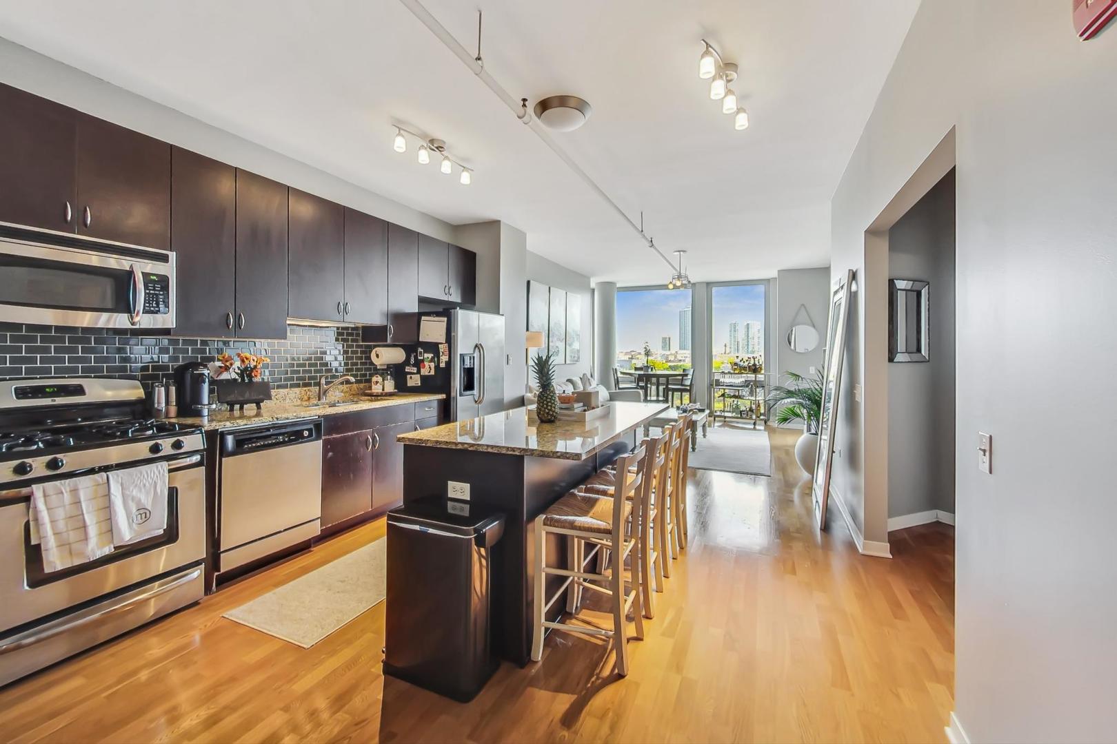 437 West Division Street, Unit 705 Chicago, IL 60610 - Photo 5 of 23 a kitchen with stainless steel appliances granite countertop a refrigerator a stove top oven a sink dishwasher and white cabinets with wooden floor