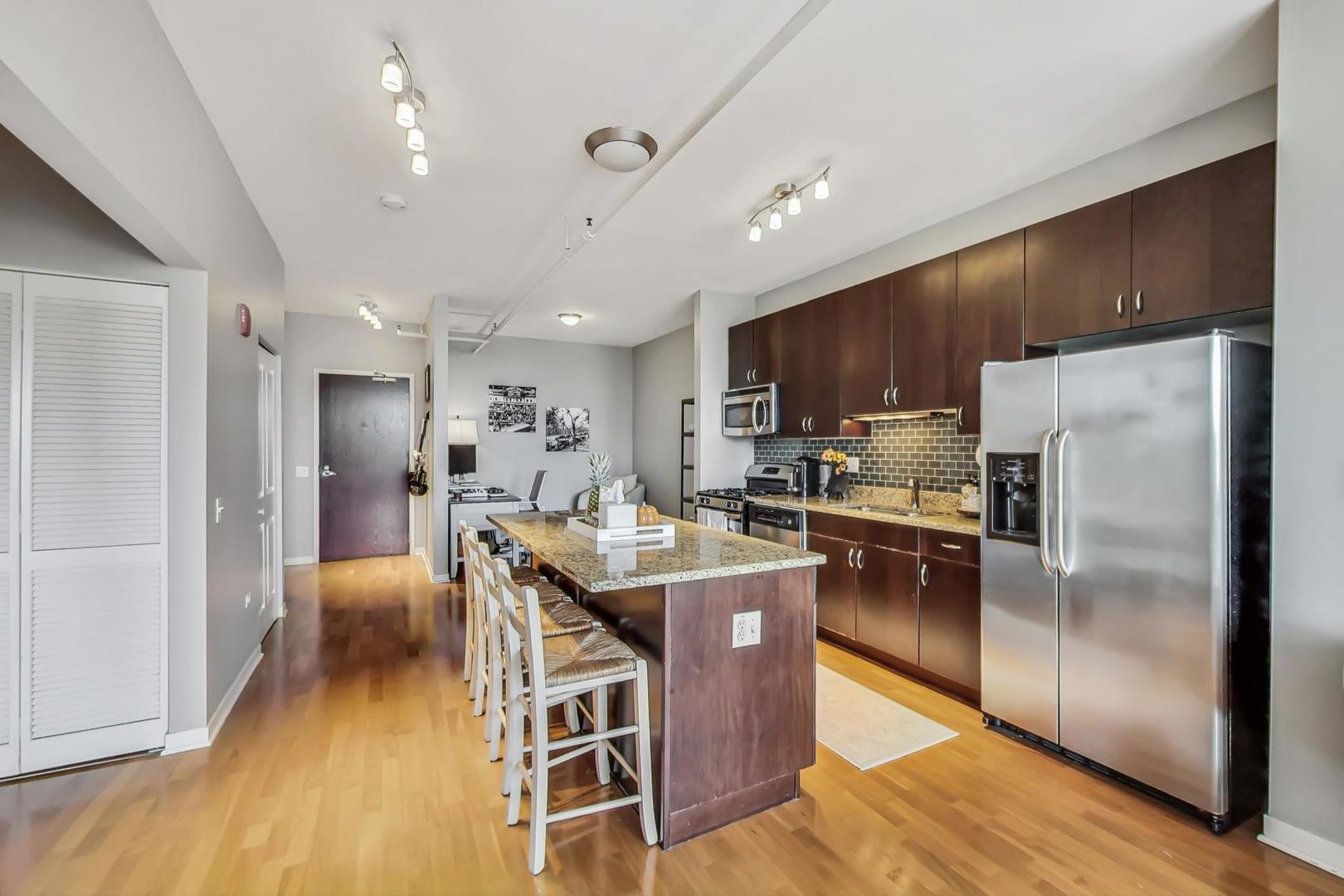 437 West Division Street, Unit 705 Chicago, IL 60610 - Photo 6 of 23 a kitchen with stainless steel appliances granite countertop a refrigerator a stove top oven a sink dishwasher a dining table and chairs with wooden floor