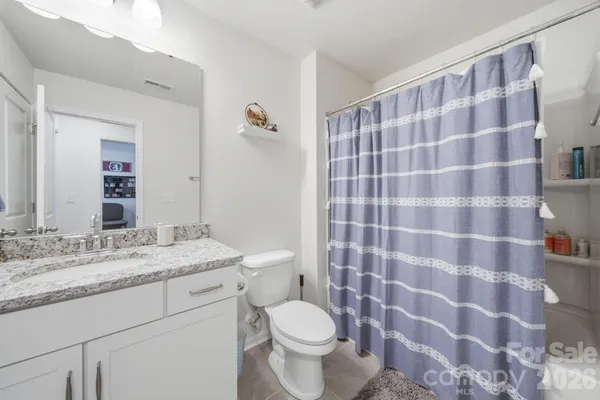 a bathroom with a granite countertop toilet a sink and a mirror