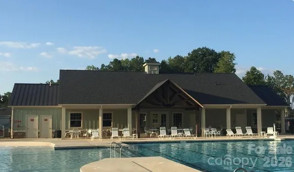 a view of house with swimming pool and outdoor seating