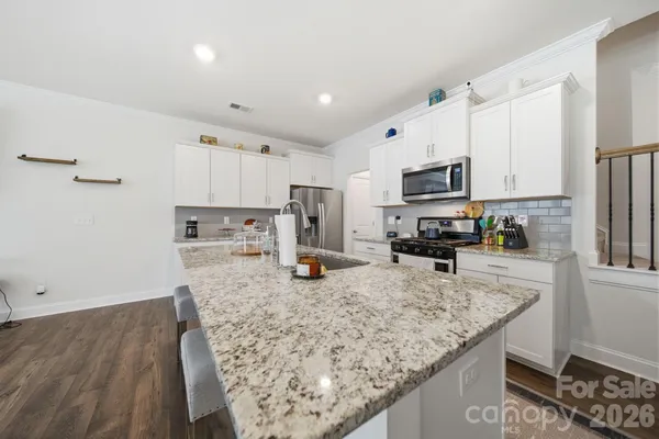 a kitchen with stainless steel appliances granite countertop a sink refrigerator and cabinets