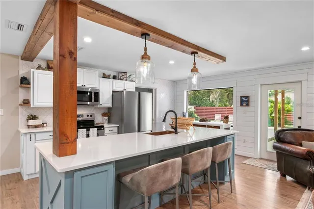 a kitchen with stainless steel appliances kitchen island granite countertop a table chairs in it and wooden floors