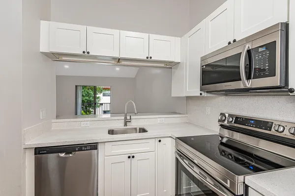 a kitchen with stainless steel appliances a stove microwave and sink