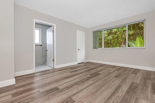 a view of an empty room with wooden floor and a window