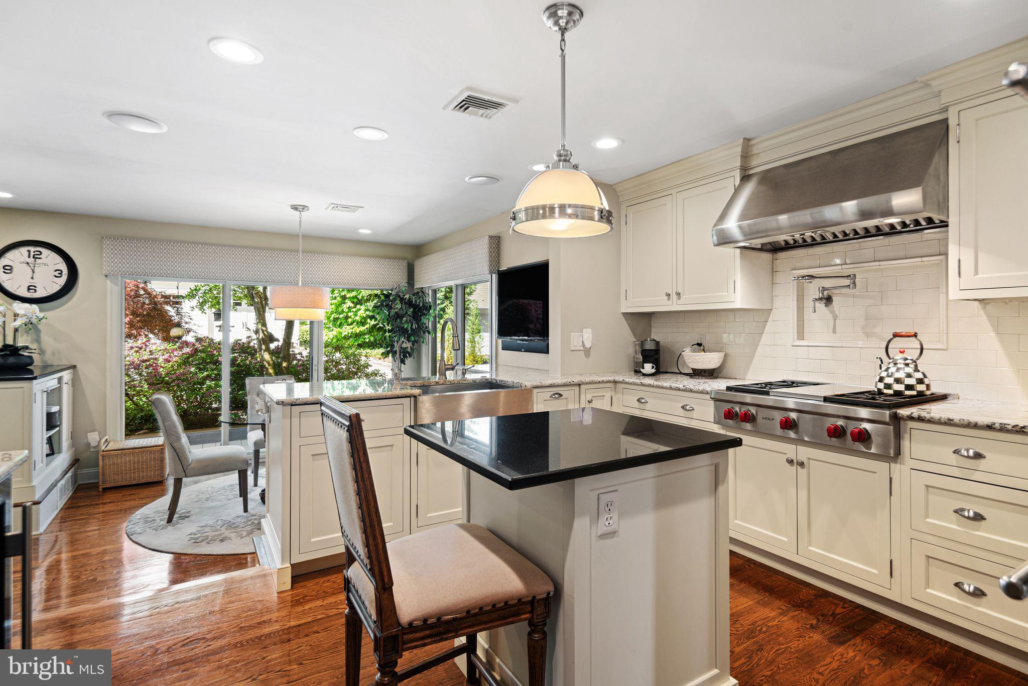 902 Warwick Road Haddonfield, NJ 08033 - Photo 8 of 43 a kitchen with stainless steel appliances granite countertop a stove a sink a microwave a dining table and chairs with wooden floor